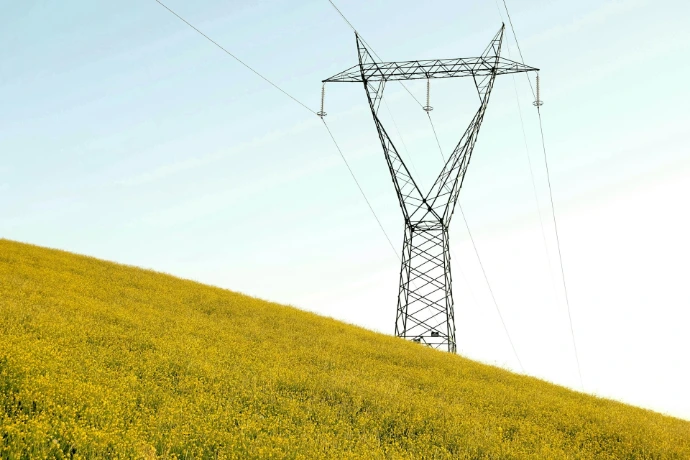 black metal electric tower on yellow grass field under white sky during daytime